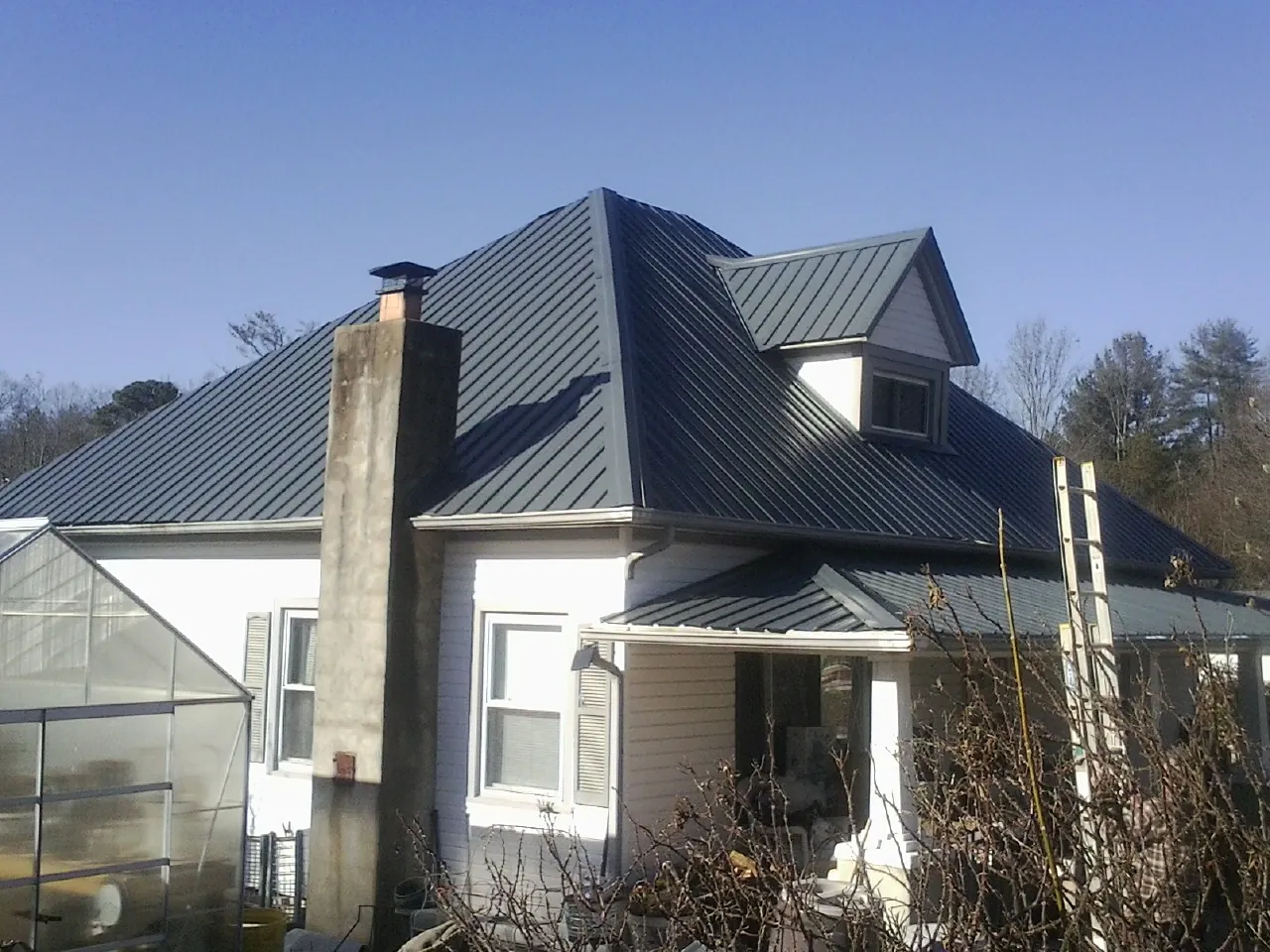 Dark blue standing seam metal roof on a white farmhouse with dormer — Slate & Tile Roof Repair by Roofing Brothers in Kennerdell
