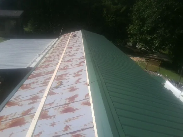 Old rusted panels beside newly installed green metal roofing — Wind Damage Roof Repair by Roofing Brothers in Kennerdell