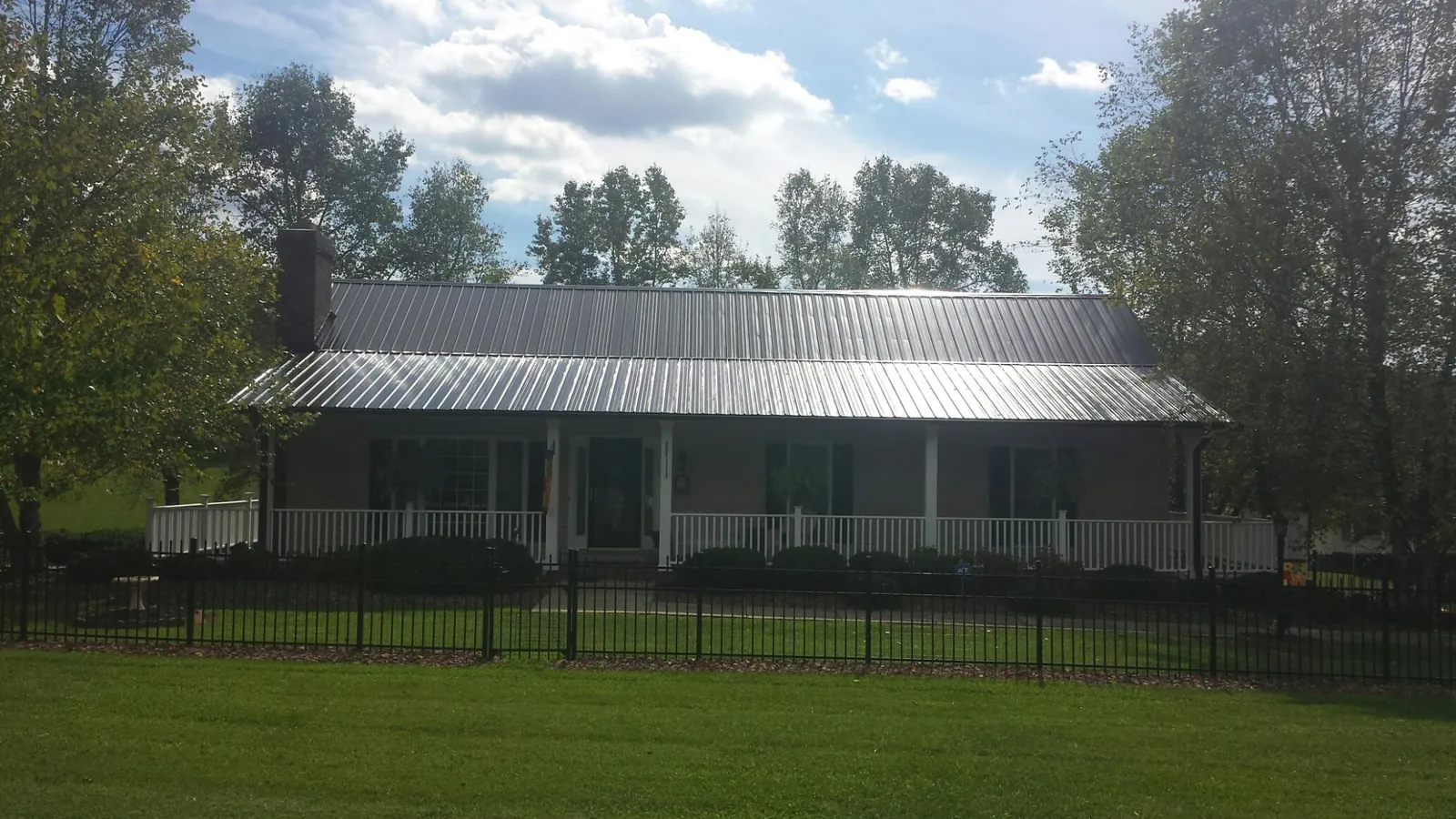 Gray metal roof on a brick ranch with a full width front porch — Gutter Guard Installation work by our crew in Kennerdell