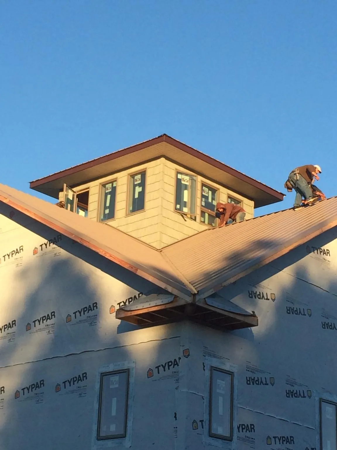 Roofers working around a rooftop cupola on a new metal roof at sunset — Roof Waterproofing in Kennerdell by Roofing Brothers